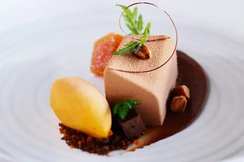 En elegant choklad havtorn dessert med en mousse, sorbet, kanderade nötter och en chokladsås.