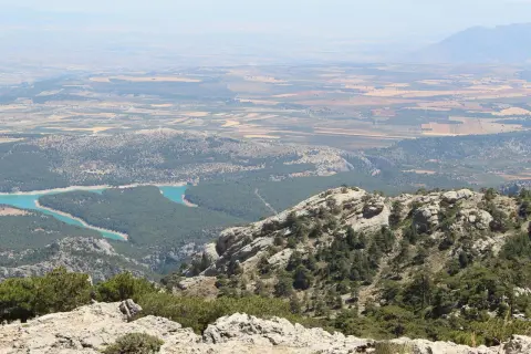Vistas panorámicas de la sierra de Cazorla, Segura y Las Villas, con un embalse turquesa y campos cultivados al fondo.
