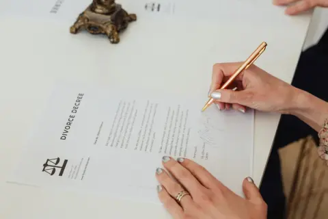 Kobieta podpisuje dokument "DIVORCE DECREE". To ważny pozew, który kończy pewien etap życia.