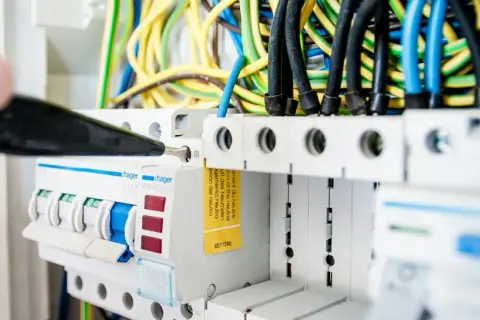 En elektriker justerar en säkring i elcentralen, en viktig del för att hålla nere driftskostnader villa.
