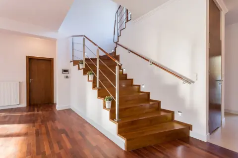 Escaleras de madera sin contrahuella, con barandilla de metal y madera, y luces empotradas. Un diseño moderno y elegante.