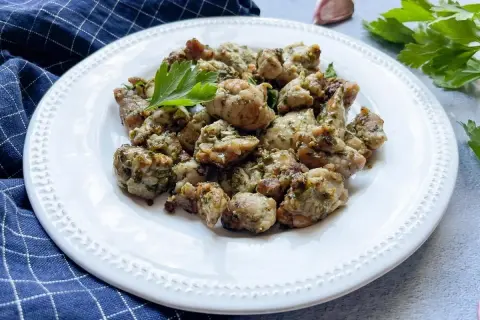 Deliciosas mollejas al ajillo, doradas y jugosas, servidas en un plato blanco con perejil fresco.