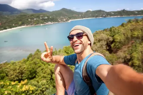 Szczęśliwy mężczyzna robi selfie na tle tropikalnej zatoki. Idealne wakacje dla singli, pełne słońca i przygód.