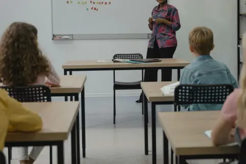 Grundschüler sitzen aufmerksam im Klassenzimmer, während eine Lehrerin eine Vertretungsstunde gibt.