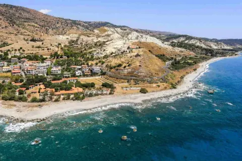 Paesaggio mozzafiato sulla **Calabria Costa Ionica**: case arroccate su colline aride, una spiaggia di ciottoli e il mare blu intenso.