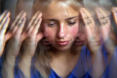 Verzerrte Ansicht einer jungen Frau mit Händen an den Schläfen, die innere Zerrissenheit und psychotische Depression erfahrungsberichte widerspiegelt.