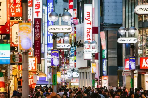 Tłoczna ulica Shibuya w Tokio, jednym z najczęściej odwiedzanych miast świata, pełna neonów i sklepów.
