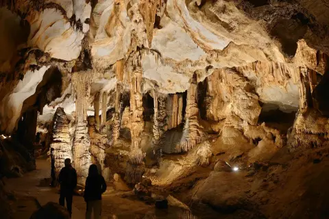 Odkrywanie najpiękniejszych jaskiń w Polsce. Dwie osoby podziwiają imponujące stalaktyty i stalagmity w oświetlonej grocie.