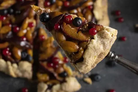Ein Stück fruchtige Galette mit Pflaumen und Beeren, perfekt für ein einfaches Galette Rezept.