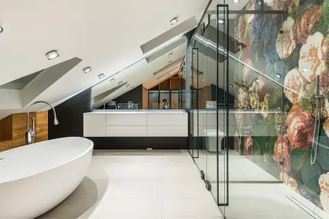 Nowoczesna łazienka z wolnostojącą wanną i prysznicem z mozaikową ścianą. Oświetlenie niskiego sufitu podkreśla architekturę wnętrza.