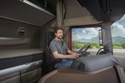 L'intérieur d'un camion DAF XG, avec un chauffeur souriant au volant, prêt pour un long voyage.