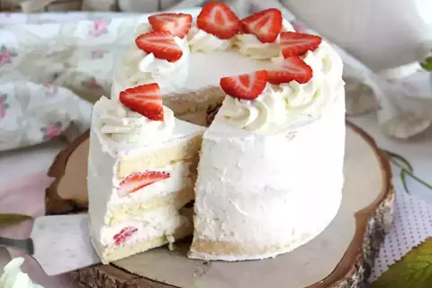 En vacker italiensk tårta med mascarpone, fylld med jordgubbar och täckt med fluffig grädde och färska jordgubbsbitar.