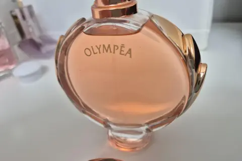 Olympea Paco Rabanne 80ml, w różowym odcieniu, otoczona złotymi zdobieniami.