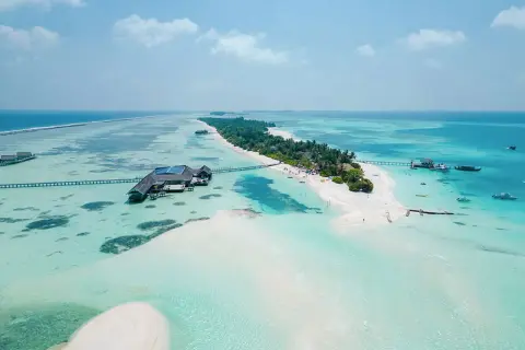 Rajska malediwy plaża z turkusową wodą, białym piaskiem i luksusowymi domkami na wodzie.