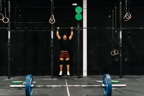 Mężczyzna wykonujący podciąganie na drążku w siłowni CrossFit.