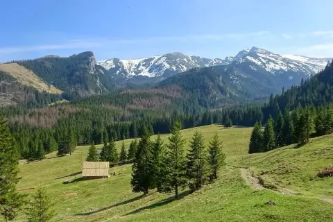 Malowniczy widok na Tatry. Drewniana chata i szlak turystyczny zachęcają do odkrywania atrakcji w górach.