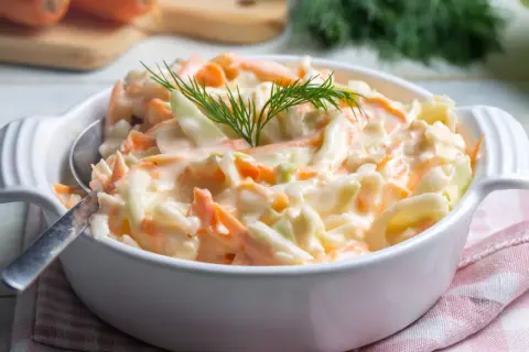 Deliciosa ensalada americana cremosa, con repollo y zanahoria rallados, adornada con eneldo fresco.