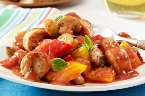 Herzhaftes Wurstgulasch mit Bratwurst, Tomaten und Pilzen, garniert mit frischen Kräutern. Ein deftiges Gericht für Genießer.