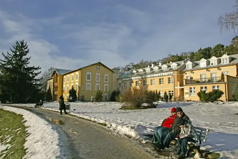 Zimowy krajobraz przed żółtym sanatorium. Zastanawiasz się, ile kosztuje turnus w sanatorium?