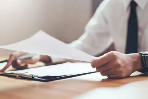 Dłoń trzyma dokumenty, analizując wielkość nabywanego udziału w prawie majątkowym.