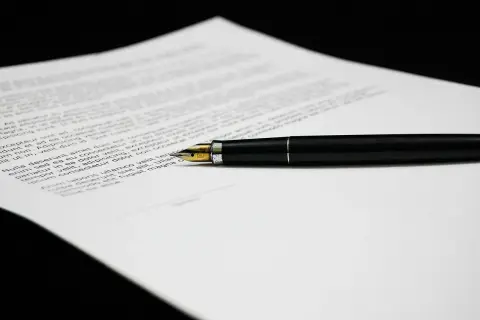 Czarny długopis na dokumencie z tekstem, który może zawierać klauzule abuzywne.