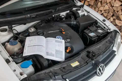 Otwarta maska samochodu z widocznym silnikiem 1.9 TDI, instrukcją obsługi i narzędziami.