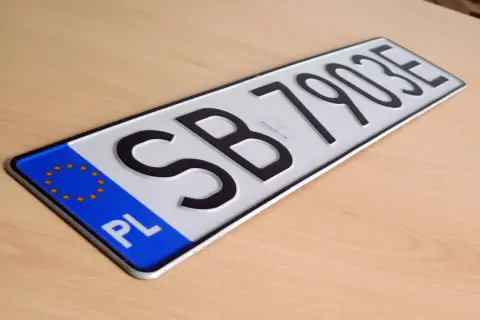 Nowe tablice rejestracyjne z oznaczeniem PL i numerem SB 79035 leżą na drewnianym blacie.