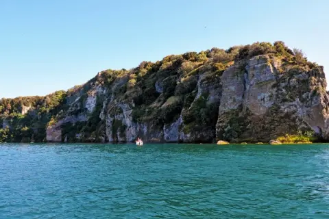 Un'emozionante visita all'isola Martana, con le sue scogliere imponenti e il mare turchese. Una piccola barca si avvicina alla costa rocciosa.