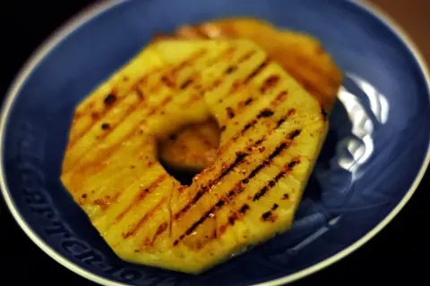 Tranches d'ananas grillées sur une assiette bleue.