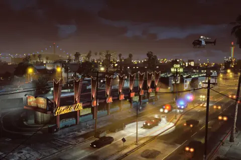 Nocne miasto w GTA 5, policyjne syreny, helikopter i neonowy szyld "Car Wash".