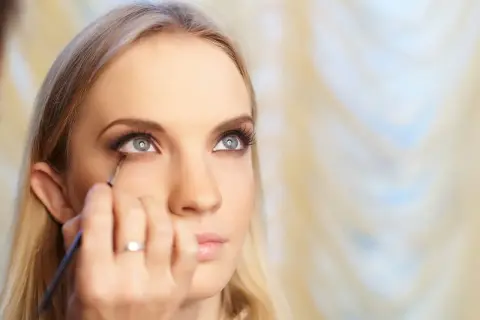 Kobieta z blond włosami otrzymuje makijaż oczu, który przypomina styl makijaż lata 20.