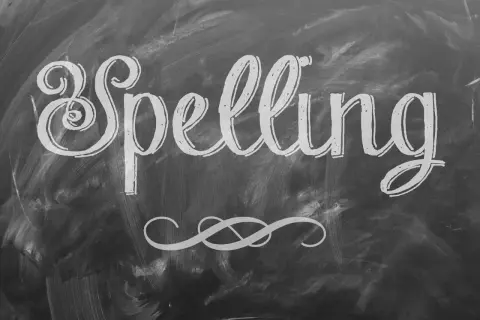 Het woord "Spelling" is met sierlijke letters op een krijtbord geschreven. Een decoratieve krul siert de onderkant.