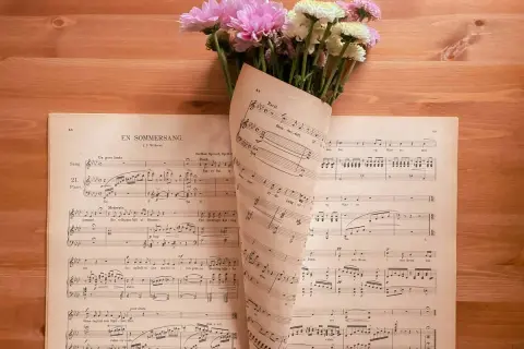 Un mazzo di fiori rosa e bianchi adagiato su spartiti musicali. Le note sembrano le canzoni della mamma, piene di dolcezza.