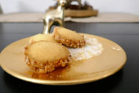 Goldene Platte mit drei Friesenkeksen, bestreut mit Zucker und gehackten Mandeln. Ein goldener Hirsch im Hintergrund. Das ist das original Friesenplätzchen Rezept.