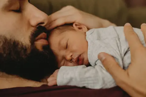 En pappa tröstar sin bebis som gråter hela tiden. Bebisen sover lugnt mot pappans bröst.