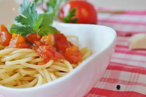 Eine Schüssel mit Spaghetti und einer herzhaften Tomatensoße, garniert mit frischem Basilikum und Petersilie.