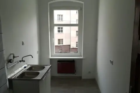 Nowe mieszkanie komunalne, gotowe do zamieszkania. Zastanawiasz się, ile wynosi czynsz za mieszkanie komunalne? Tutaj jest kuchnia z dwukomorowym zlewem i widokiem na podwórko.