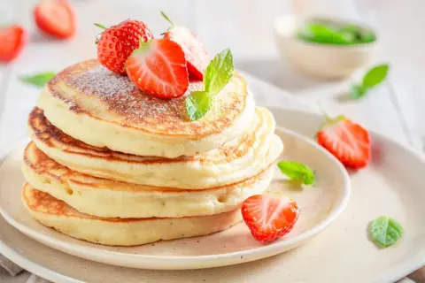 Pancakes soffici con fragole e menta, una deliziosa colazione proteica dolce per iniziare la giornata con energia.