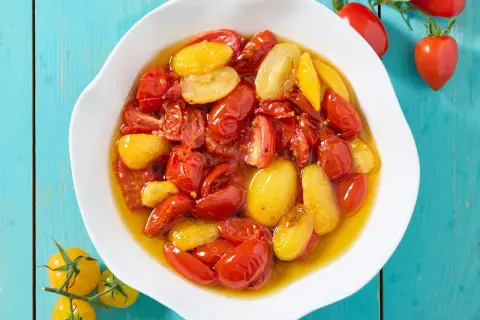 Pomodorini confit in friggitrice ad aria, rossi e gialli, immersi in olio profumato, pronti per insaporire ogni piatto.