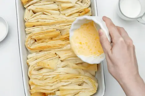 Przygotowanie ciasta filo. W miseczce jajko, obok cukier i mleko. Czas na pyszne przepisy!