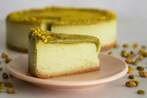 En krämig pistage cheesecake med en krispig botten, toppad med hackade pistagenötter.