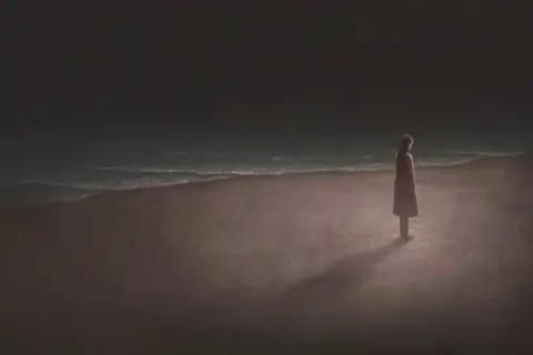 Una persona sola en la playa, contemplando el mar. Reflexiona sobre las cosas que tienes que hacer antes de morir.