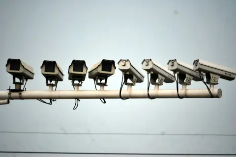 Reihe von Überwachungskameras vor grauem Himmel.