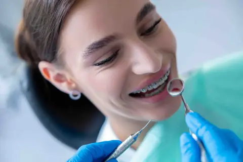 Sorriso con apparecchio ortodontico, mentre il dentista esamina i denti. Nessun mal di denti apparecchio, solo un controllo di routine.