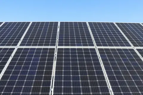 Duża instalacja PV pod błękitnym niebem. Panele słoneczne tworzą równą, ciemną powierzchnię, gotową do produkcji czystej energii.