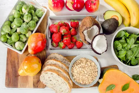 Zdrowe produkty na talerzu: brukselka, truskawki, jabłka, banany, awokado, szpinak, dynia, gruszki, chleb i płatki owsiane. Idealne składniki na dietę 1800 kcal.