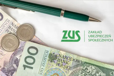 ZUS i polskie złotówki, gotowe do opłacenia składek. Zielony długopis czeka na podpis.
