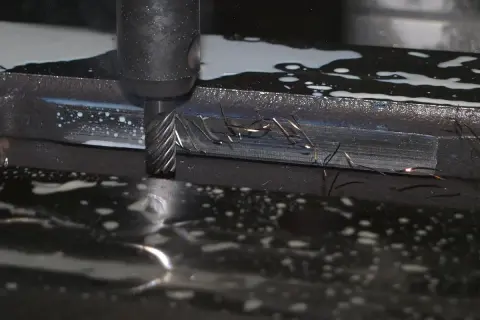 Frezowanie detalu podczas produkcji małoseryjnej. Wióry metalu unoszą się w chłodziwie, tworząc iskry.