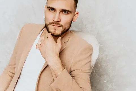 Elegancki mężczyzna w beżowej marynarce, zamyślony, być może zastanawia się, czego pragną mężczyźni.