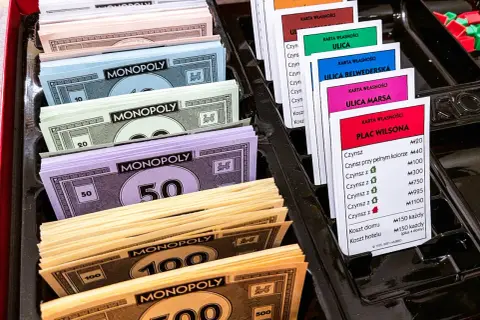 Monopolowe banknoty o nominałach 10, 20, 50, 100 i 500 oraz karty własności nieruchomości.
